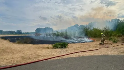 Leicestershire Police Firefighter dealing with burning grass at Aylestone Meadows in Leicestershire