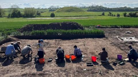 Archaeologists dig on a muddy site 