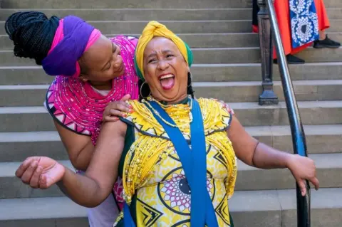 PA Wire Woman laughing in yellow traditional African clothes