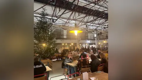 Supplied People sat inside Glossop Market Hall with a decorated Christmas tree on display to the side