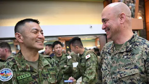AFP via Getty Images A Japanese officer in military uniform smiling at a US officer in military uniform