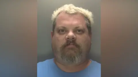 Leicestershire Police A police mugshot of James Siddell. He is wearing a blue t-shirt and has short bleach blonde hair.