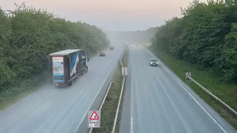 A view of the A6 near Mountsorrel, Leicestershire, taken from a bridge with a haze towards the sky 