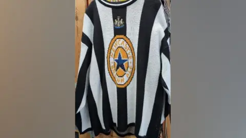 Tina Scott A Newcastle knitted jumper which is black and white with the Newcastle Brown Ale logo on the front 