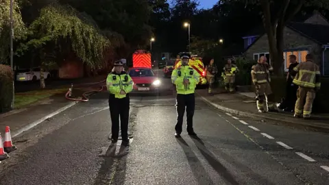 BBC/Charles Heslett Police officers standing near a fire engine