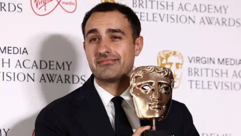 Reuters Jamie Demetriou holding his Bafta Award