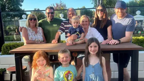 Lori Carnochan Family photograph. Three children at the front, six adults and small child at the back.