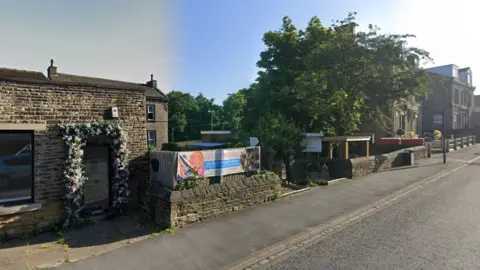 A building behind a low Yorkshire stone wall. A sign reading Cute Companies is placed across the wall. A large tree is on one side of the wall.