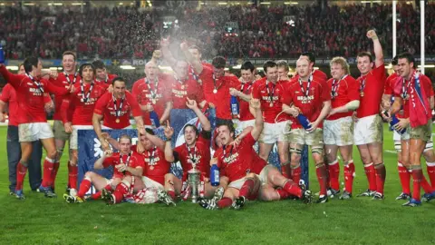 Getty Images Wales players celebrate on the pitch - they are all in red shirts and white shorts.
