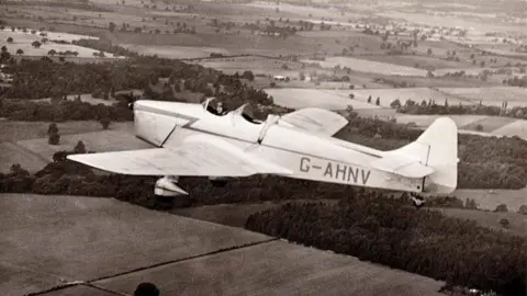 National Trust An archive photograph of a Wellington Bomber flying over the countryside. The aircraft is above fields and trees around Croome Court.