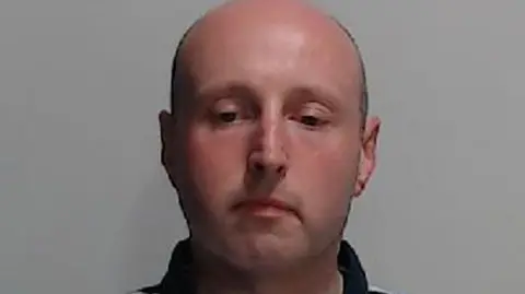 Police Scotland Ross Jameson mugshot. A bald man wearing a blue, white and yellow striped polo-shirt. 