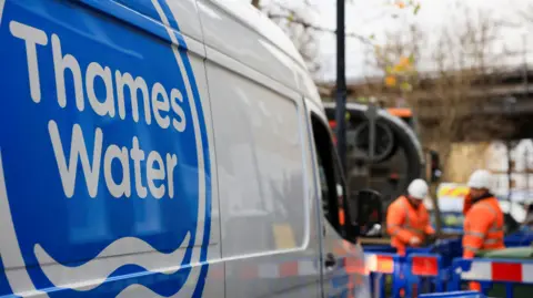 Thames Water employees carry out repair and maintenance next to a van with the company's logo on.