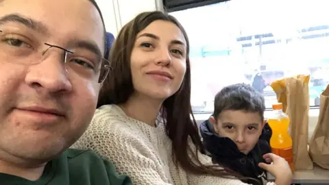 Nathan Rossiter, his wife Olena and son Leo sitting aboard a train