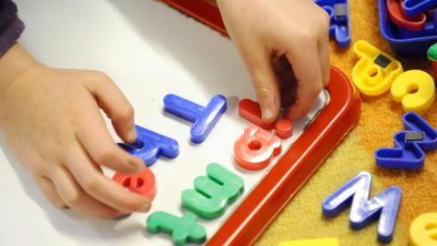 A stock image of a child using a magnetic alphabet
