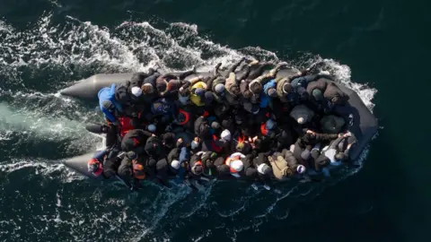 An inflatable dinghy carrying around 65 migrants crosses the English Channel.