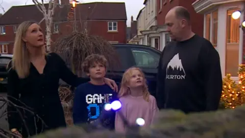 Family looking up at decorations outside their front door.