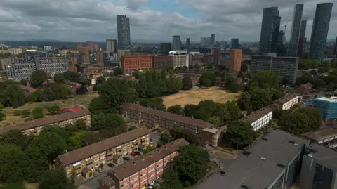 An aerial photograph taken with a drone shows high-rise towers behind social housing blocks in Manchester.