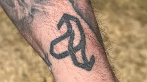 A tattoo of the Tramlines logo with parallell lines pointing arrows in two directions.