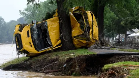 AFP A van crushed by the torrents is pressed against a tree in Germany