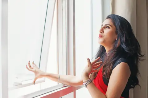 Getty Images Woman opening window due to extreme heat