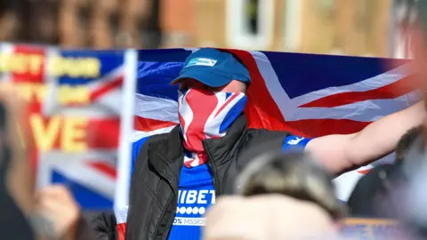 Pacemaker Man wearing blue Rangers shirt and union flag face covering