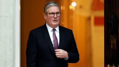 EPA Sir Keir Starmer wearing dark suit and glasses away from camera as he steps out of the front door at Number 10, in London on 14 January