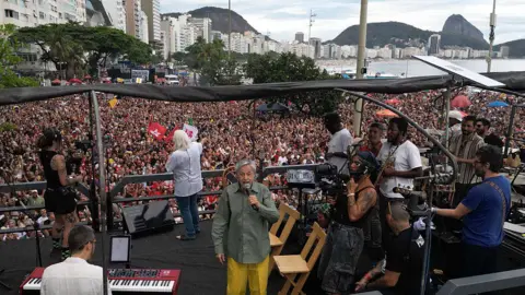 Getty Images This aerial view shows Brazilian artist Caetano Veloso (C) performing during a protest against the Brazilian Congress to reject a bill that would modify penalties for crimes against democracy and thus reduce the sentence of former president Jair Bolsonaro, at Copacabana Beach in Rio de Janeiro, Brazil on December 14, 2025.