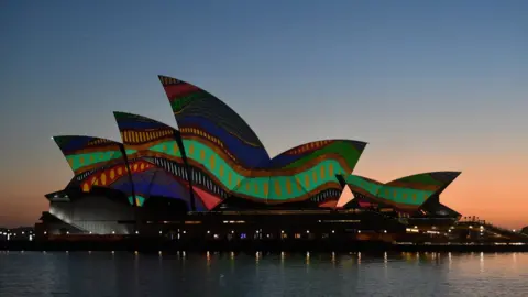 EPA The sails of the Sydney Opera House are lit up at dawn with an artwork by Indigenous artist Frances Belle-Parker