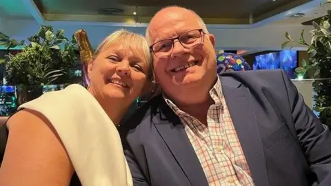 Mary Turner and David Ross left to right sat close together, Mary has her head on David's shoulder