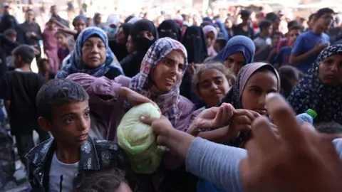 AFP Palestinians wait in a queue to receive bread outside a bakery in Khan Younis, in the southern Gaza Strip (29 October 2024)