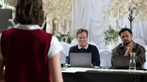 Audition room with actor trying out for the role of Belle in front of a panel, including Gareth Gates, sitting at a table