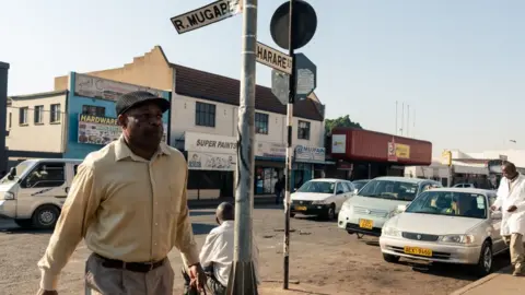 Getty Images Pedestrians walk along Robert Mugabe Road in the capital Harare on September 6, 2019