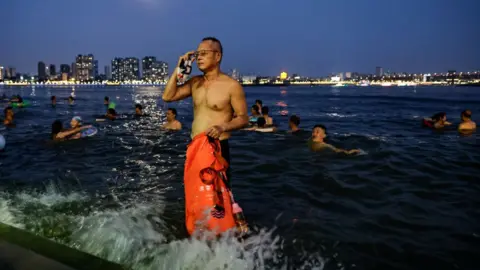 Getty Images People swim in the intersection of the Han and Yangtze rivers during the heatwave in Wuhan, Hubei province on 10 August