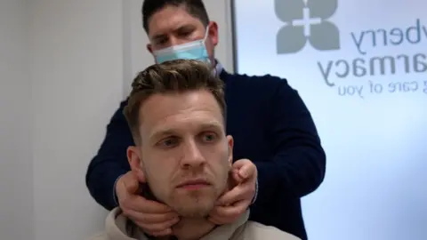 Pharmacist Jonathan Smith checks Jack Rollings' glands