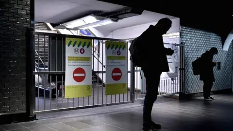 AFP Passengers stand in front of the closed gates of the Châtelet metro station in Paris on 10 December 2019