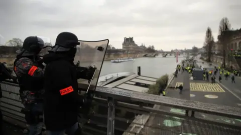 EPA French riot police stand guard on a bridge over the Seine river overlooking protesters below as clashes erupt during a "yellow vests" protest in Paris, on 5 January 2019