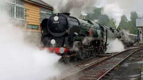 A 1940s Bulleid Pacific steam locomotive at the Swanage Railway platform, enveloped in steam