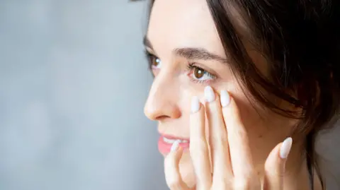Getty Images Woman applying eye cream