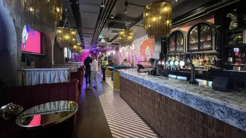 Long bar with tables and a stage at the end