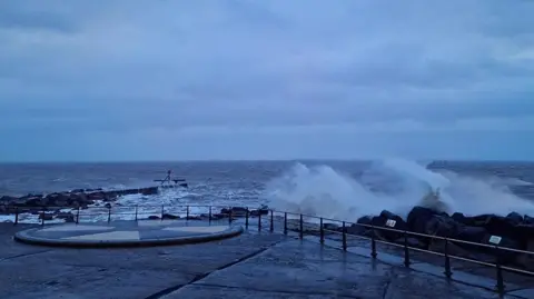 BBC Weather Watchers / whethertheweatherbefine Lowestoft seafront, with waves crashing against rocks during Storm Bert