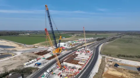 HS2 An aerial view of a construction site with cranes over a long stretch of dual carriageways. 