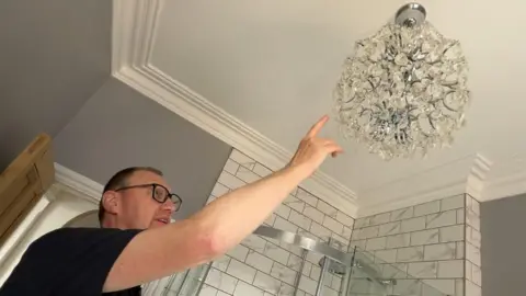 Rob Wilson points at a chandelier. 
