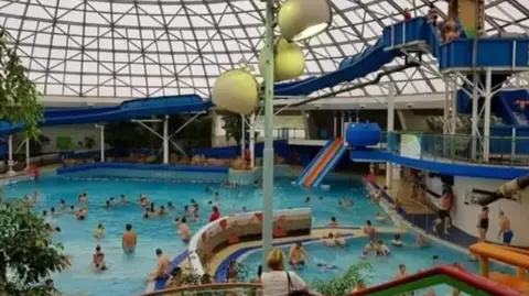 Save Oasis Swindon Oasis leisure pool in action, with various slides and many people playing in the water. The famous domed roof with its metalwork lattice sits atop.