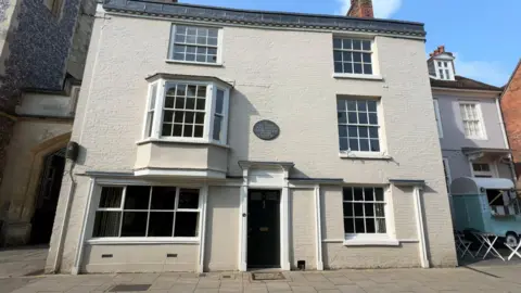 The outside of a white brick building with three stories in a city street