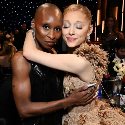 Getty Images Cynthia Erivo and Ariana Grande embracing in evening dress