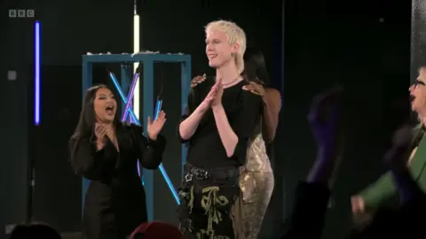A shot from the finale of BBC Three's Glow Up, showing other competitors congratulating Jake after he was announced as winner.