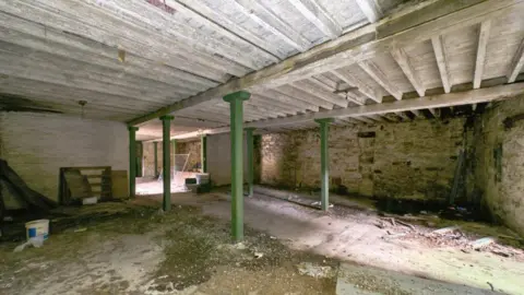 Shepherd An empty building with green pillars holding up a wooden roof
