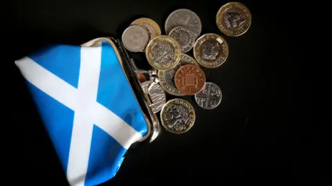 PA Media A saltire logo on the front of a purse with loose change spilling out onto a black surface