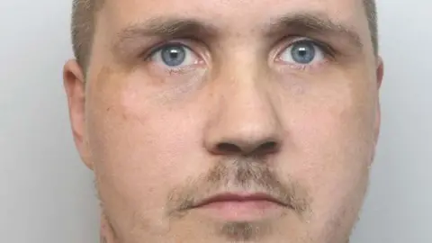 Cheshire Police Christopher Foster's mugshot. He has blue eyes and a moustache. He is against a clear white background. 