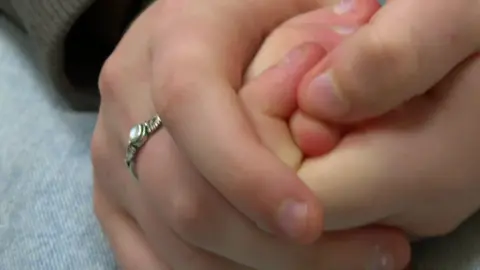 A close-up of a girl holding her hands together. She has a ring on her middle finger on her left hand. 